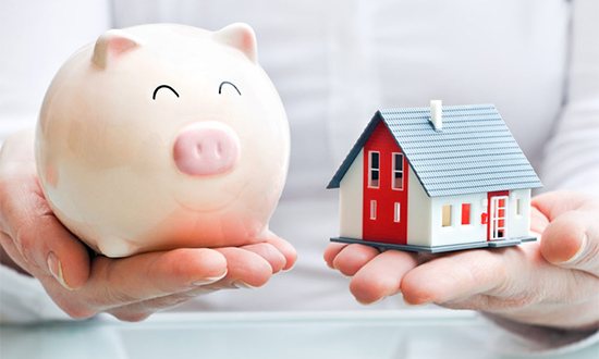 Hands holding a piggy bank and a house model. Save money when moving.