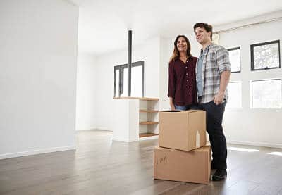 Excited Couple Standing With Boxes In New Home On Moving Day!