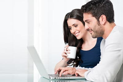 Happy modern couple working on laptop at home and leaving a 5 star moving company review
