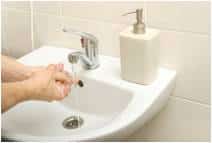 Sink with soap container and woman washing hands