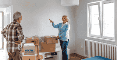 Two senior citizens in the middle of a move with packed boxes