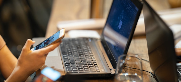 A person using a phone and a laptop