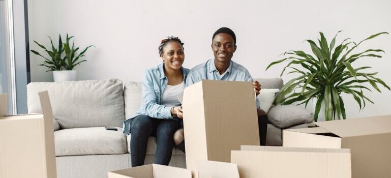 A couple sitting near boxes waiting for movers Branford CT