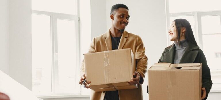 couple holding boxes while waiting for their movers New Canaan CT locals love