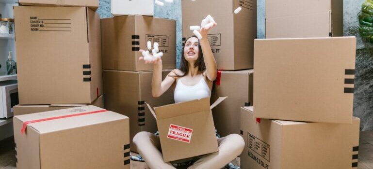 A woman sitting among moving boxes and waiting for movers Westport CT