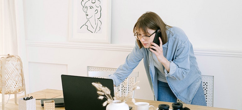 A woman using a laptop and a phone in her home office