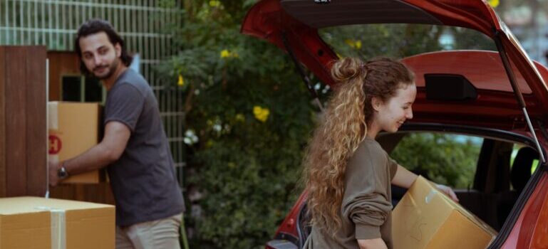 couple unpacking boxes from their car