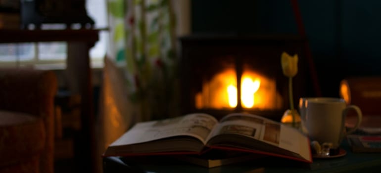 Book and a drink in front of a fireplace during a snowy day in Brookfield CT