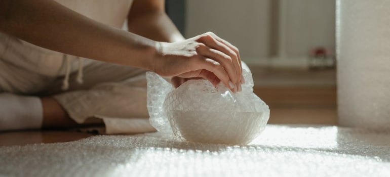 Person packing items in bubble wrap and getting it ready for storage alternatives