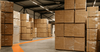 Storage warehouse with pallets of stacked boxes on a clean floor.