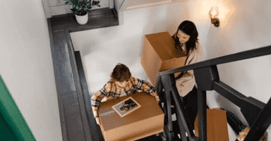 A family carrying boxes upstairs while waiting movers Monroe CT to arrive